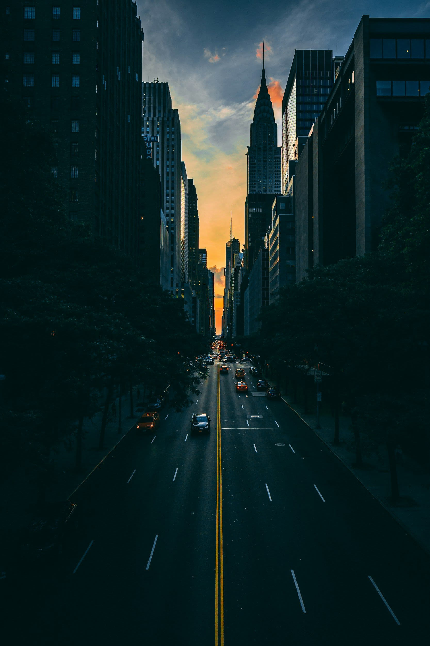New York City street at sunset with tall skyscrapers on either side.